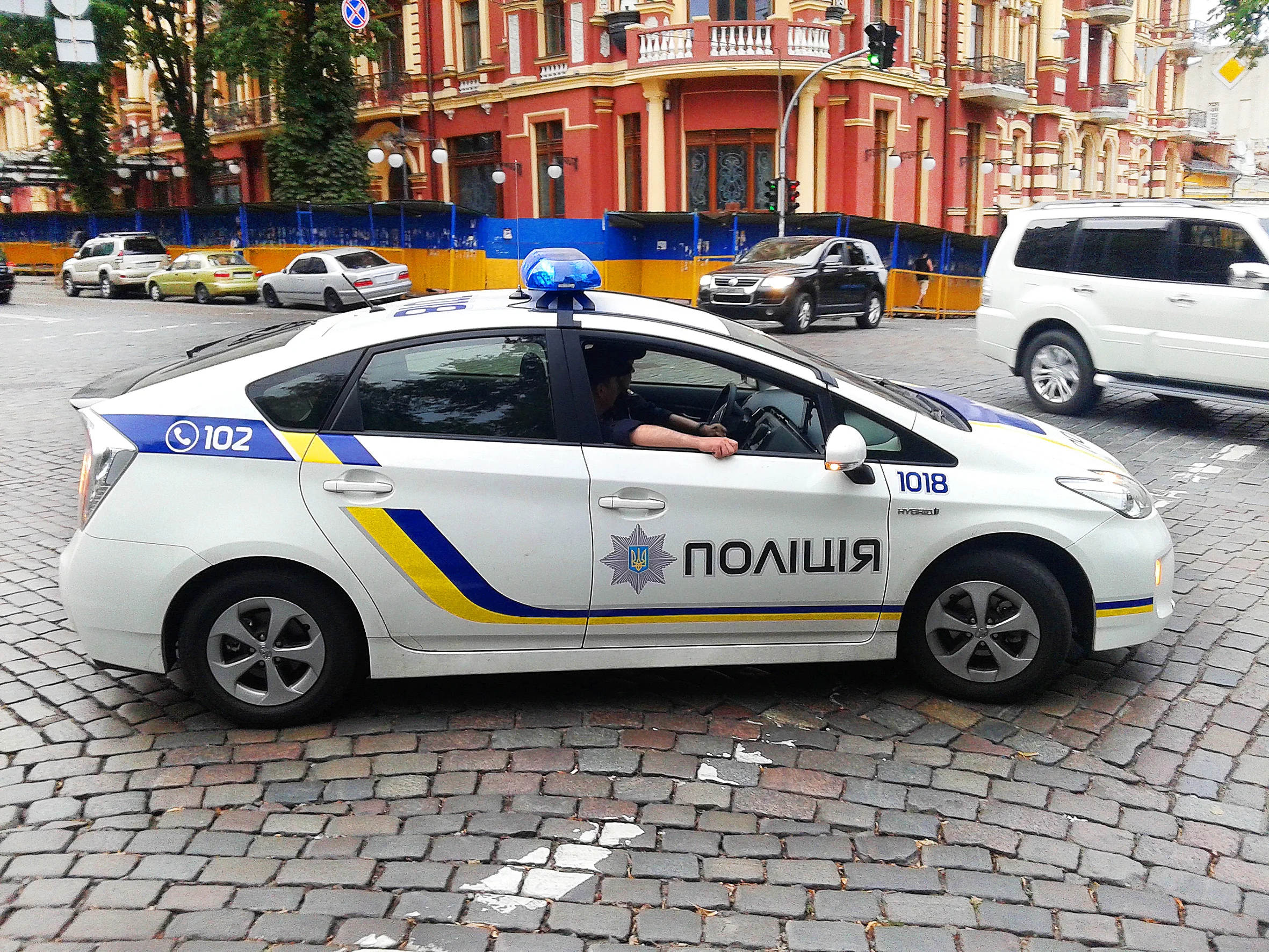 Білий поліцейський Toyota Prius з написом ПОЛІЦІЯ на бруківці міста